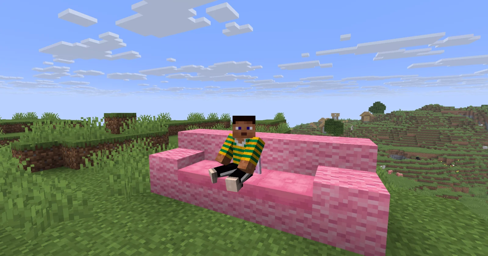Joueur assis sur un canapé rose construit avec des coussins dans Minecraft